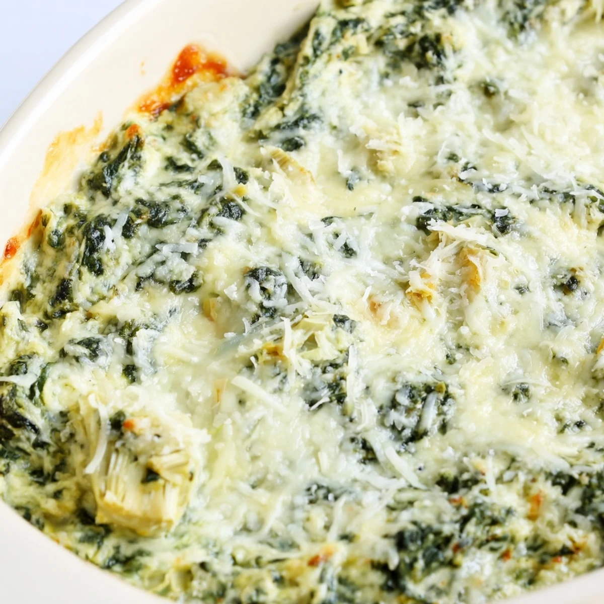A close-up of creamy Cheesy Spinach Artichoke Dip, rich in color, ready to be scooped up.