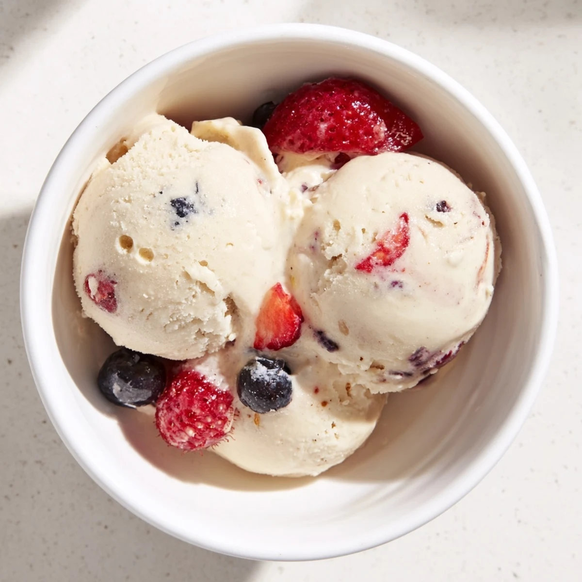 A vibrant scoop of Cottage Cheese Ice Cream, swirled with purple berries, is ready to be enjoyed.
