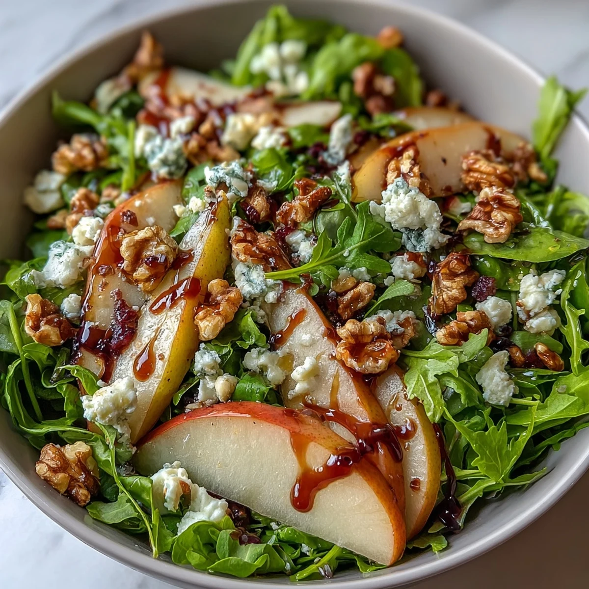 A close-up of a vibrant Arugula and Pear Bowl featuring peppery greens, sweet pears, and creamy goat cheese with balsamic drizzle.