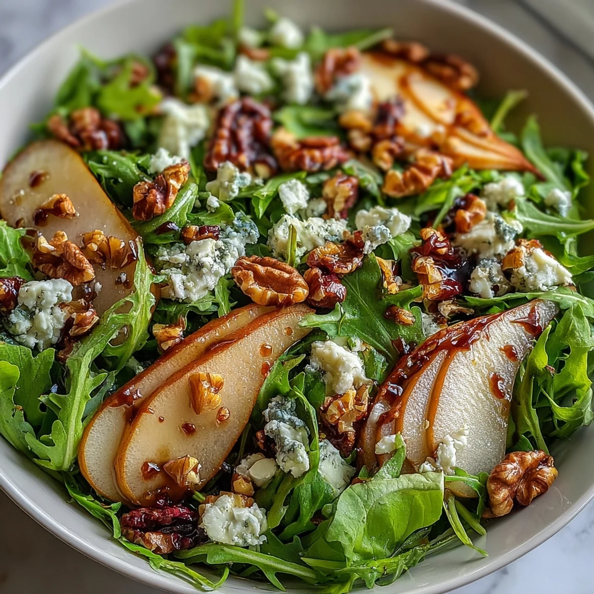 Overhead view of a large Arugula and Pear Bowl tossed with walnuts, sliced pears, and fresh greens, ready to serve.