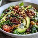 A vibrant Mixed Greens Power Bowl with colorful vegetables and a zesty lemon dressing, served on a white plate.