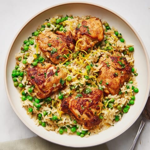Hearty one-pot creamy lemon chicken and rice with golden chicken thighs, peas, and vibrant herbs.