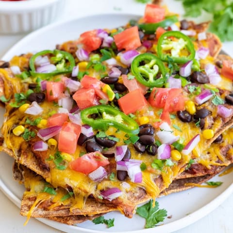 Sheet pan nachos with bubbly cheese and colorful toppings, perfect for a Tex-Mex feast.