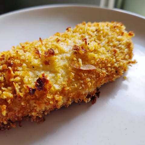 Golden roasted garlic Parmesan chicken breasts garnished with fresh parsley, resting on a white ceramic plate for a weeknight dinner.  