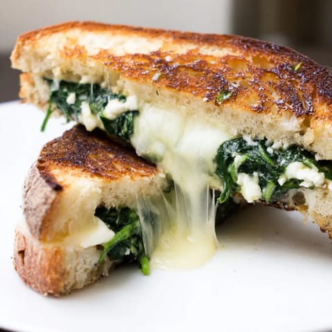 Hearty Feta & Spinach Stuffed Grilled Cheese with sautéed greens, paired beside a warm bowl of tomato soup.