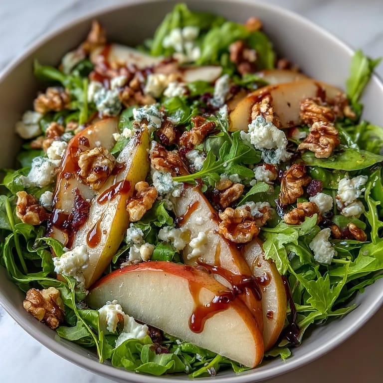 A close-up of a vibrant Arugula and Pear Bowl featuring peppery greens, sweet pears, and creamy goat cheese with balsamic drizzle.