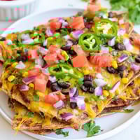 Sheet pan nachos with bubbly cheese and colorful toppings, perfect for a Tex-Mex feast.