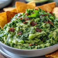 Creamy edamame guacamole with ripe avocado, fresh lime, and cilantro, served with crisp golden pita chips.  