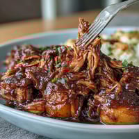 Summer Crockpot Honey Peach BBQ Pulled Pork in crockpot with sliced peaches and rich sauce.